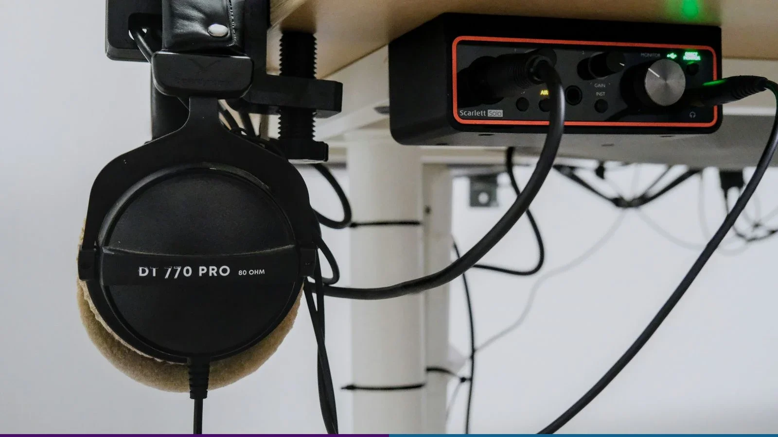 Fone Beyerdynamic DT 770 Pro ao lado de uma interface Focusrite Scarlett Solo em uma mesa de gravação